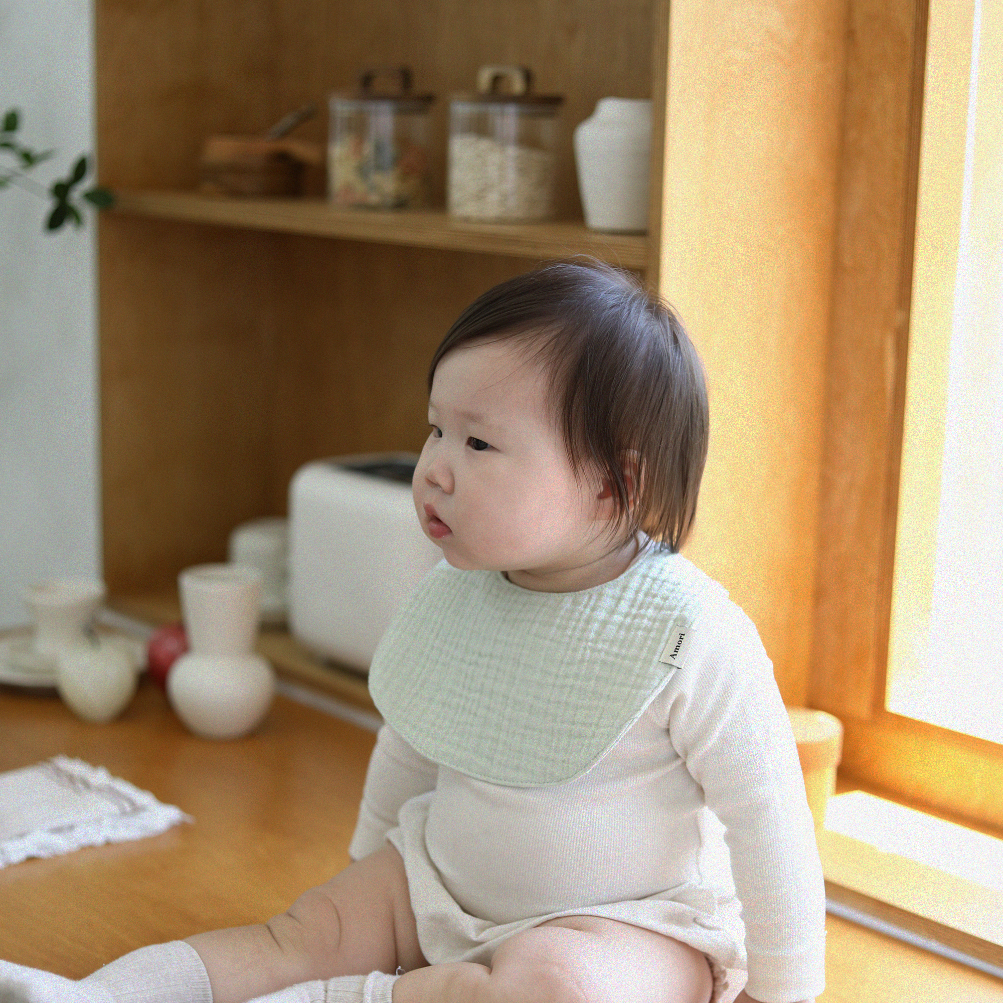아모리 Mint 거즈빕 아기 실내에서 옆을 바라보는 모습